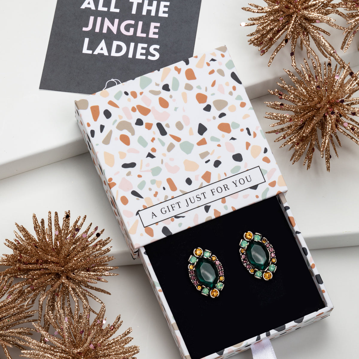 Green-centred multicolour crystal stud earrings in a gift box with festive decorations
