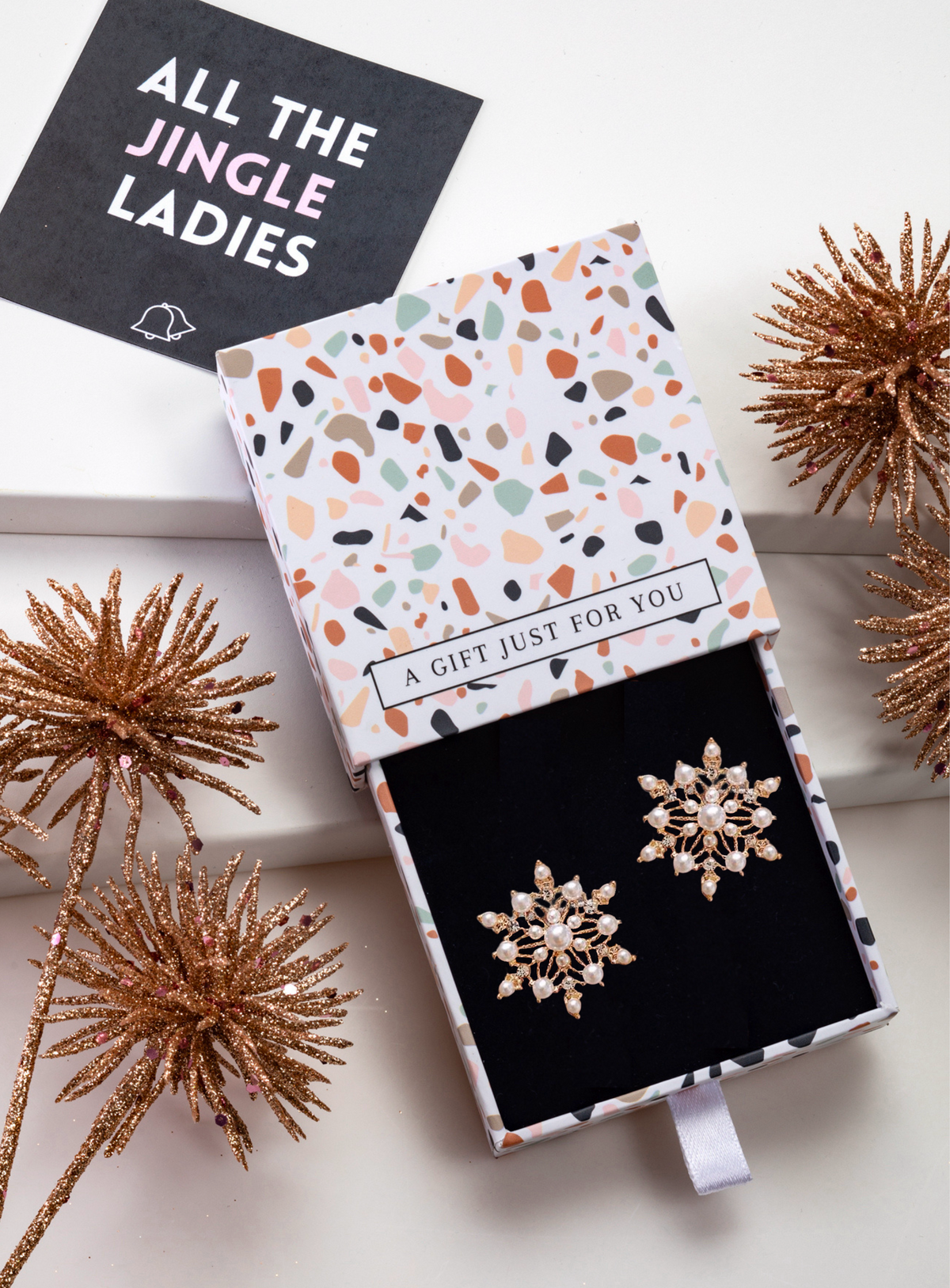 Gold-tone faux pearl snowflake studs inside an open patterned gift box