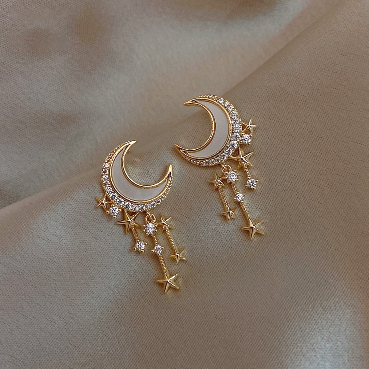 Close-up of goldtone cubic zirconia crescent moon earrings with dangling stars