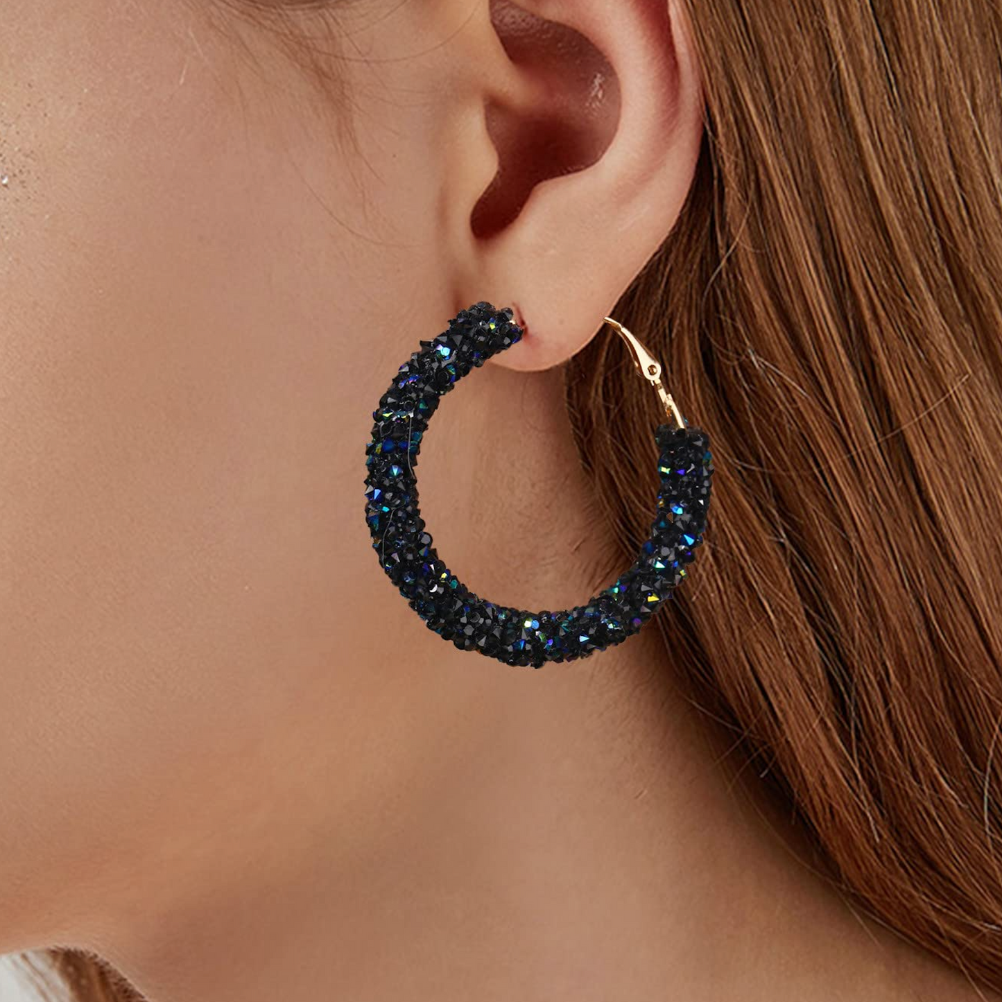Close-up of a person wearing a sparkling hoop earring.