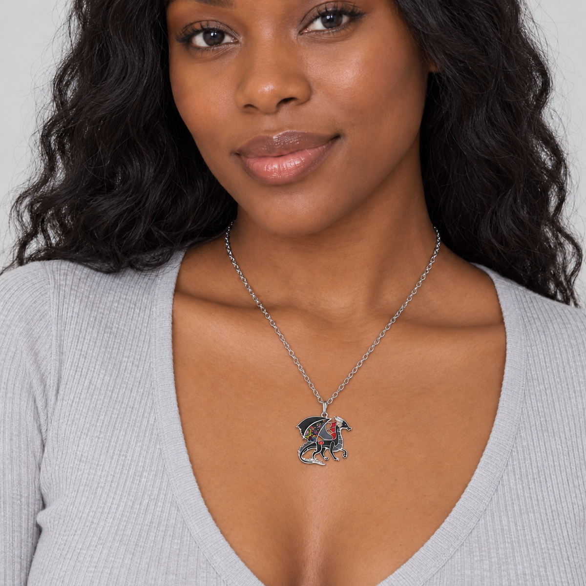 Small black enamel dragon pendant necklace worn by a model in a pale grey top