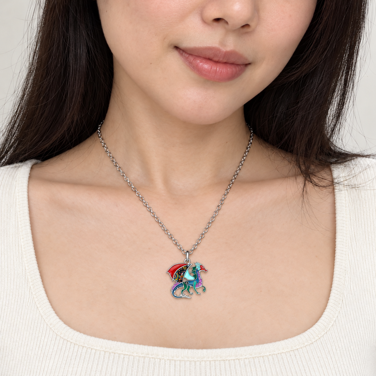 Small multicolour enamel dragon pendant necklace worn by a model in an ivory top