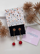 Gold-tone red snowflake chain earrings with red bead drops in an open gift box