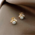 Gold-tone bee stud earrings with white faux pearl bodies on satin