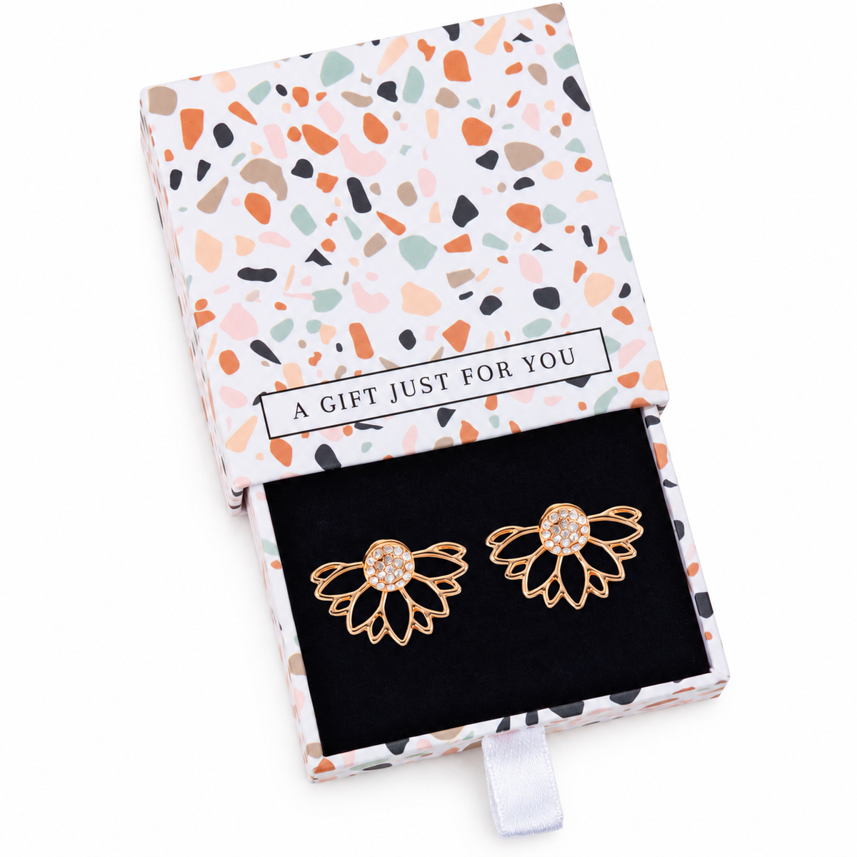 Gold-tone crystal lotus ear jackets in their terrazzo-patterned gift box on a white background