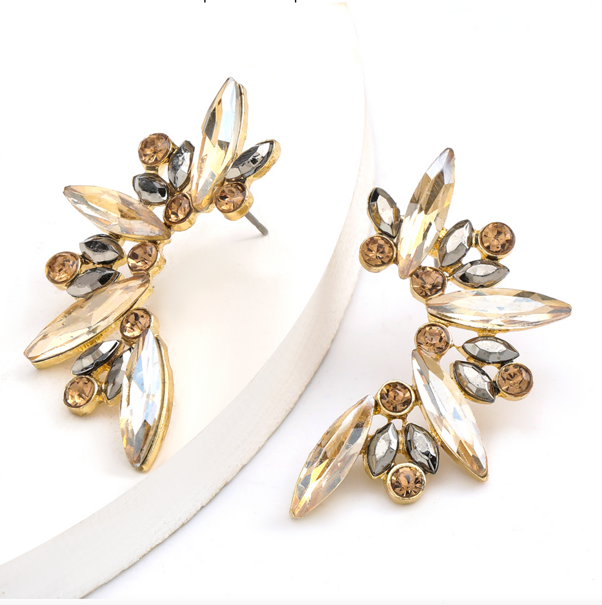 Gold-tone marquise crystal cluster earrings displayed on a white block