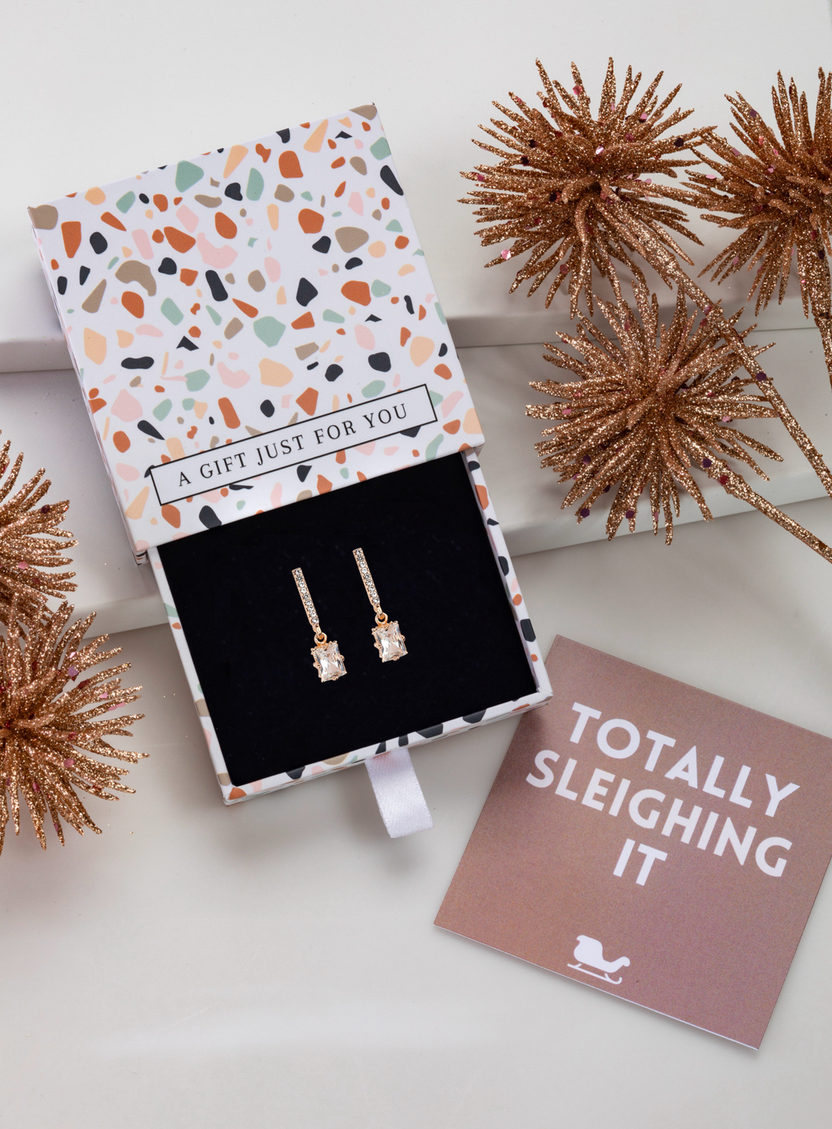 Cubic zirconia bar and baguette drop earrings in a patterned gift box with festive styling