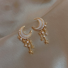 Close-up of goldtone cubic zirconia crescent moon earrings with dangling stars