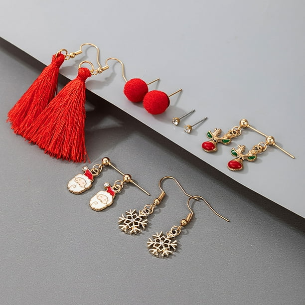 Red and gold-tone Christmas earrings arranged diagonally on a white block