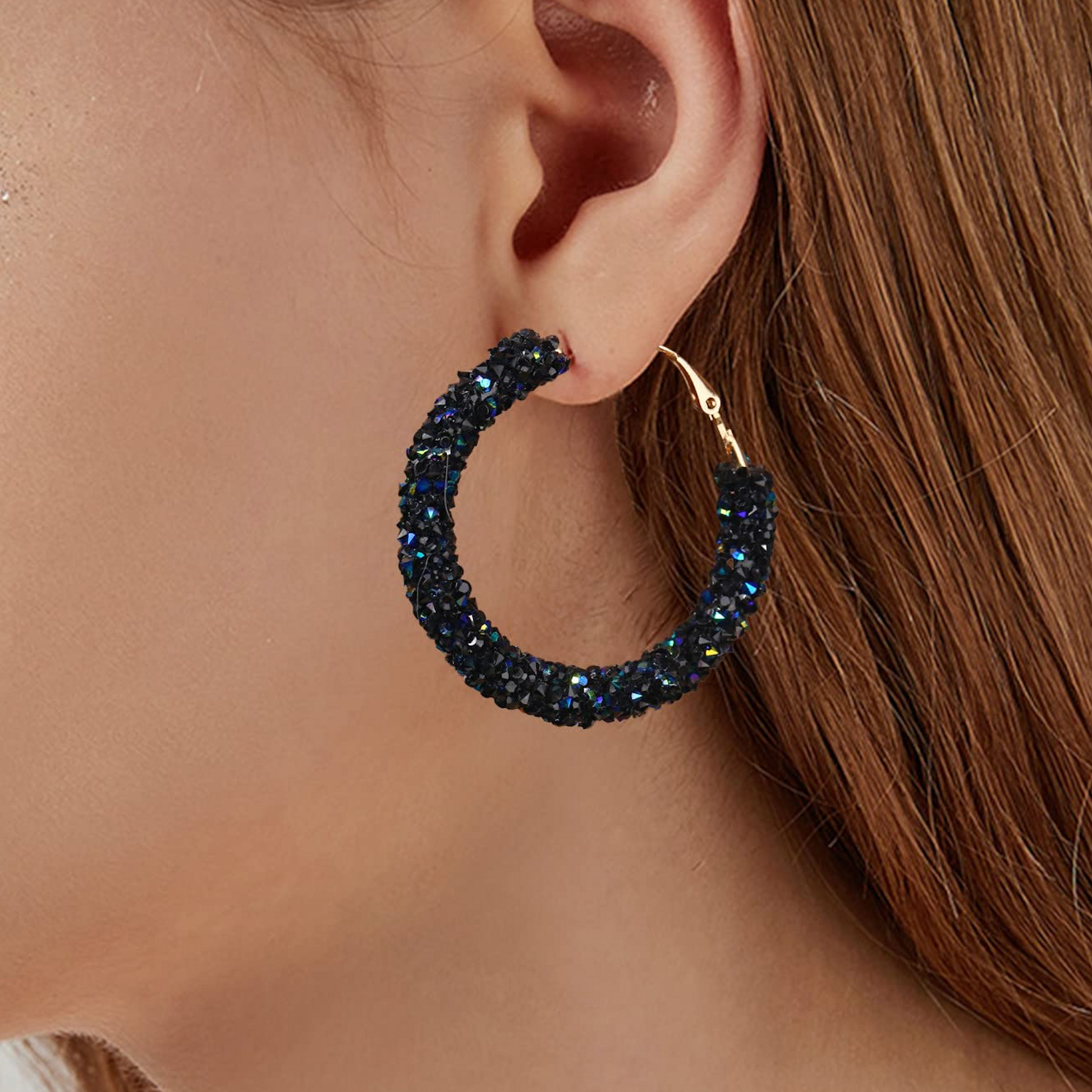 Close-up of a person wearing a sparkling hoop earring.