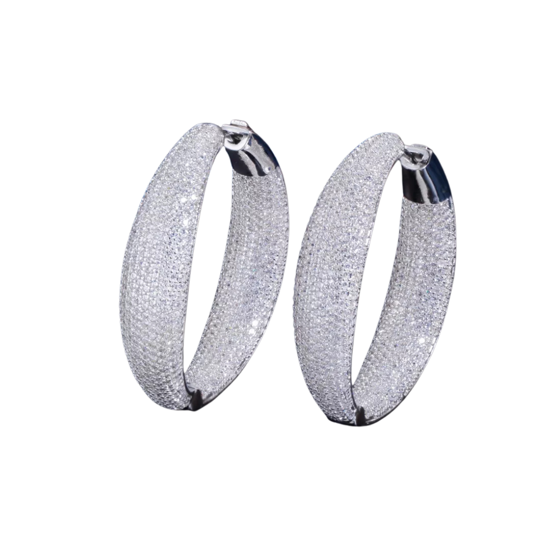 A pair of silvertone hoop earrings with cubic zirconia pave-set stones on a white background.