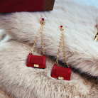 A pair of red and goldtone crystal-accent fashion clutch chain drop earrings displayed on a white surface with a furry texture.