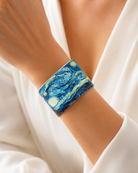 Close-up of a blue night-sky print cuff on a wrist with a white sleeve