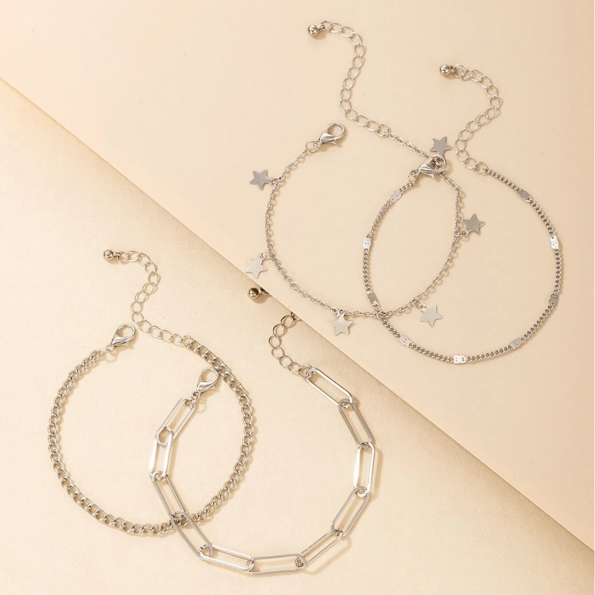 Silver-tone star charm and chain-link bracelet set, angled flat lay