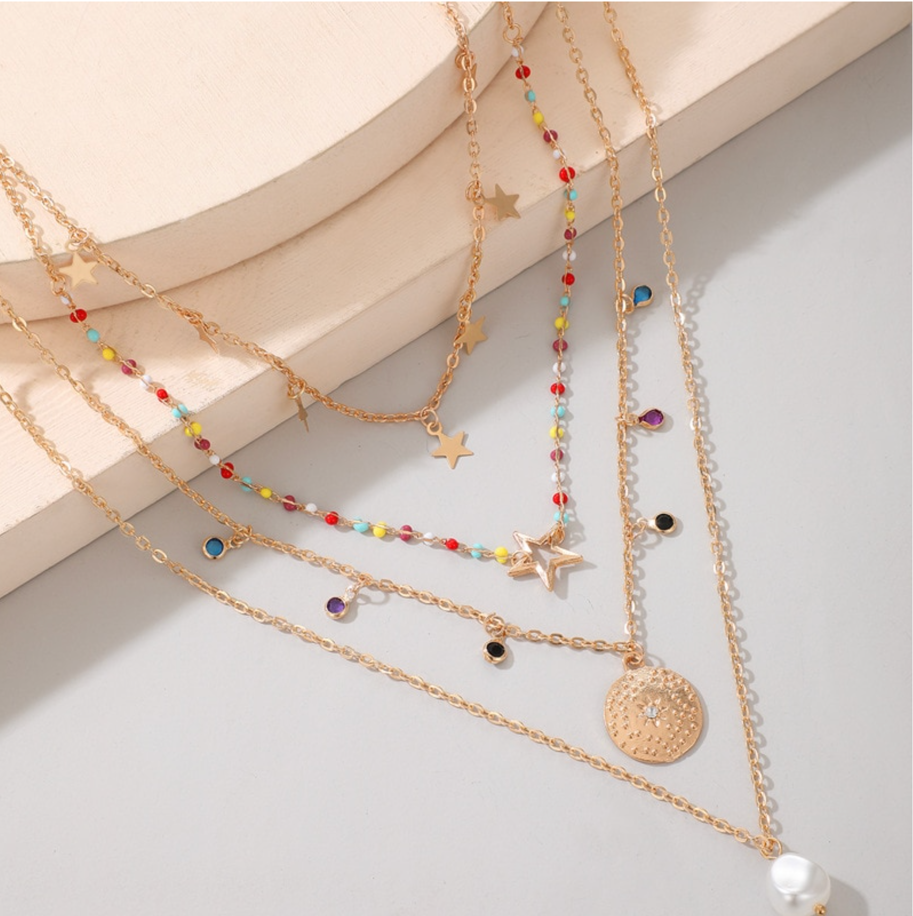 Gold-tone layered necklace with colourful bead accents, disc charms and a faux pearl pendant