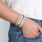 Model wearing a sand and white braided and beaded faux leather wrap bracelet