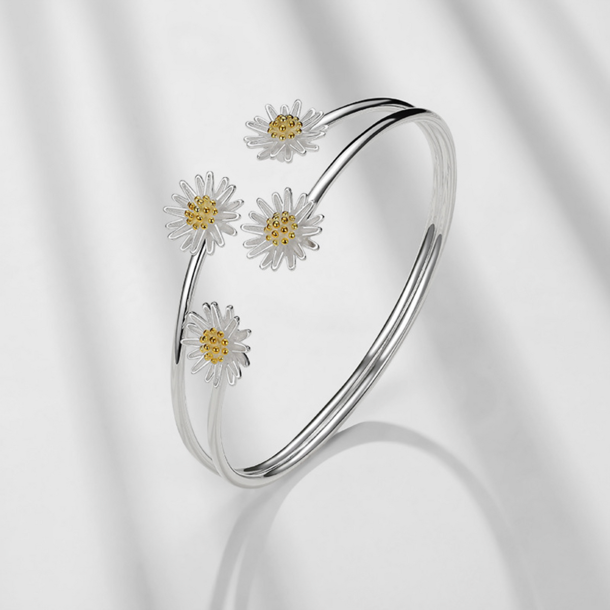 Silver-tone daisy bangle displayed on a white stand, angled view