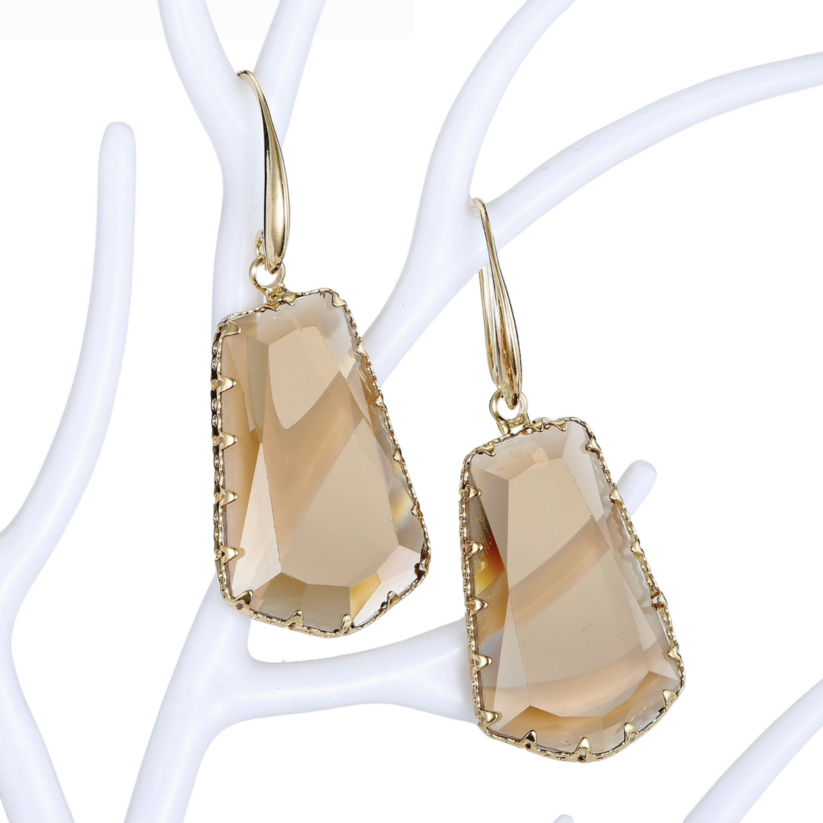 Champagne crystal drop earrings with goldtone hooks on a white display stand