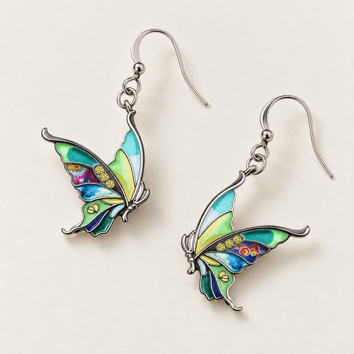 Green enamel butterfly earrings arranged diagonally on an ivory surface