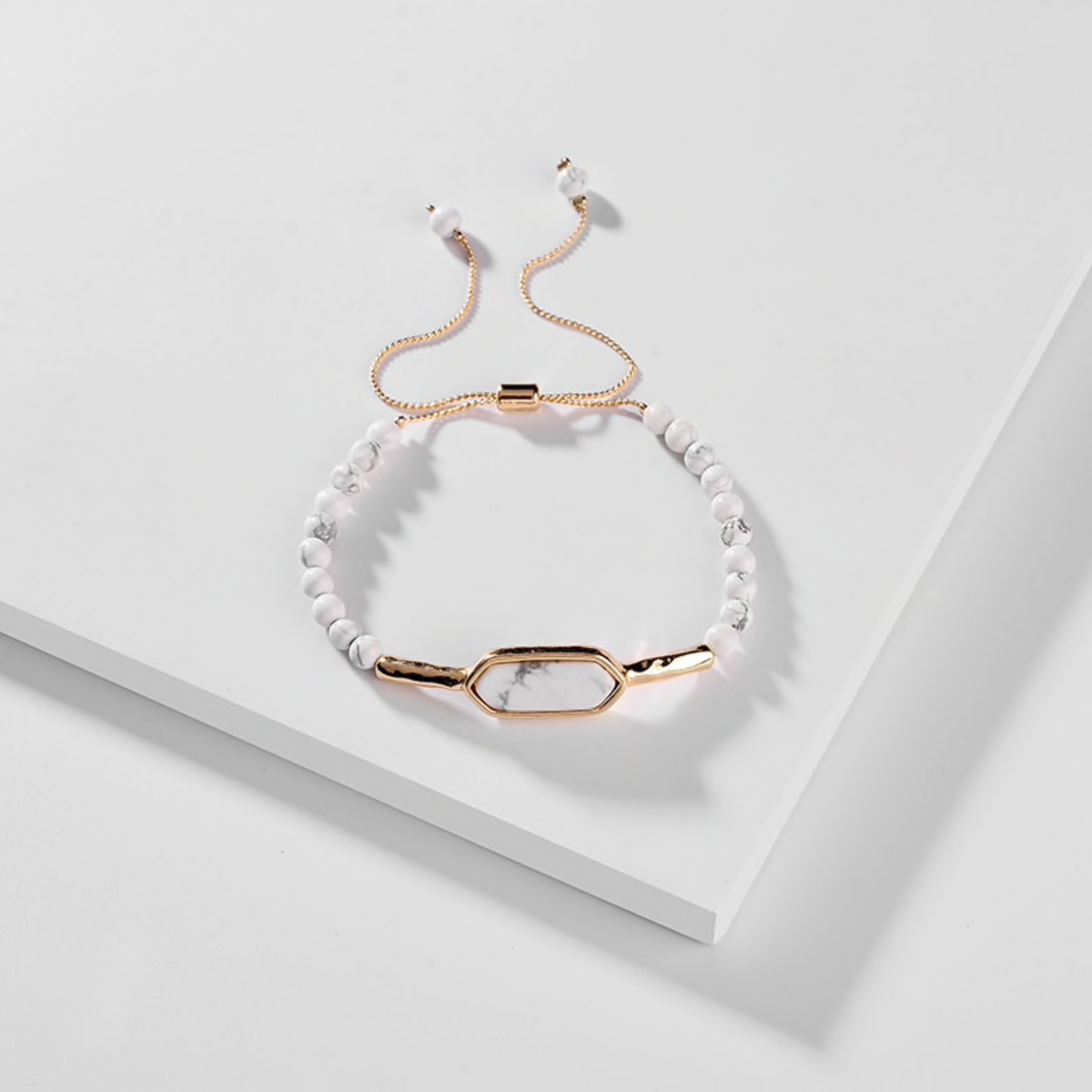 White marbled bead bracelet with gold-tone oval link and adjustable chain on a white box