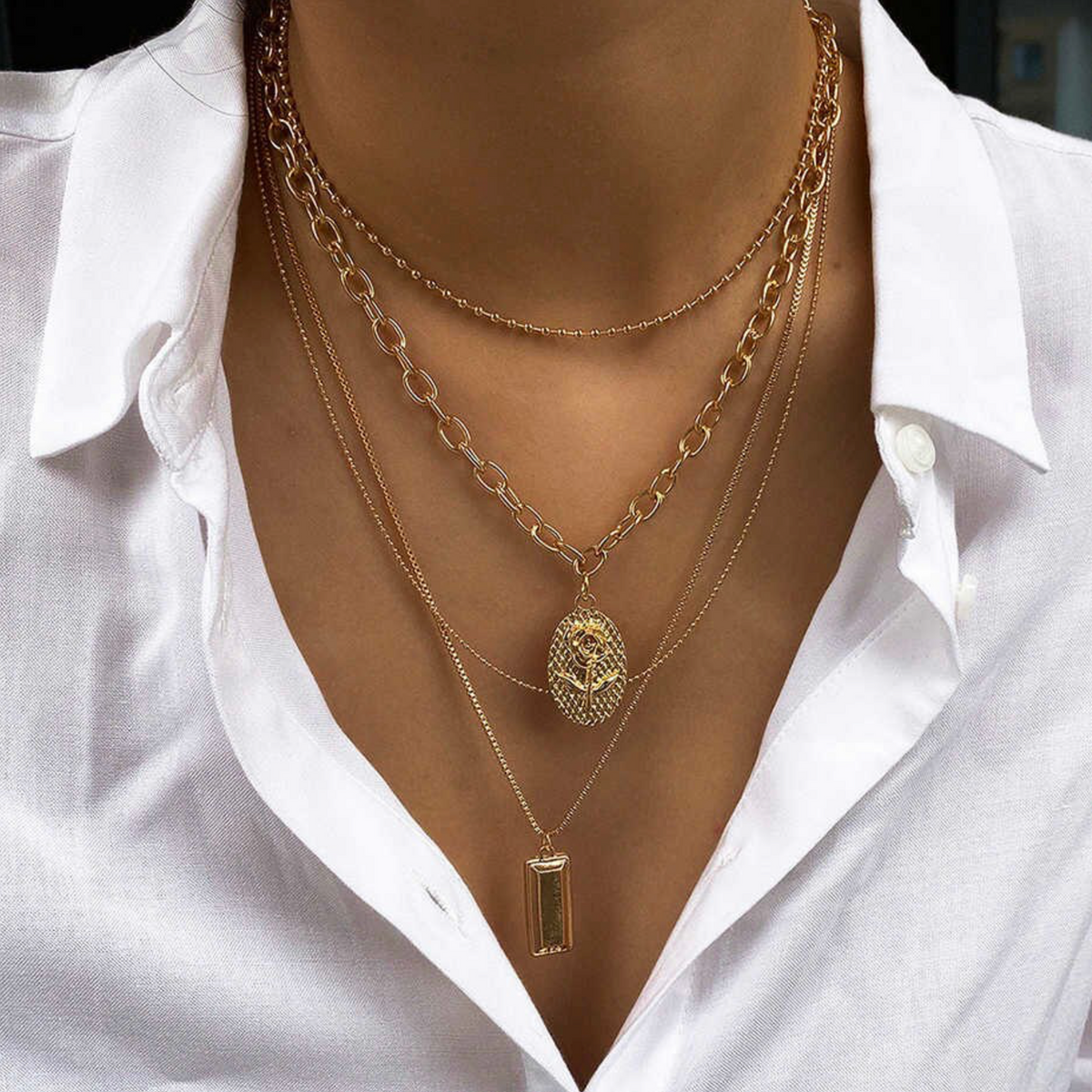 Goldtone mixed chain necklaces with floral and rectangular pendants worn on a model