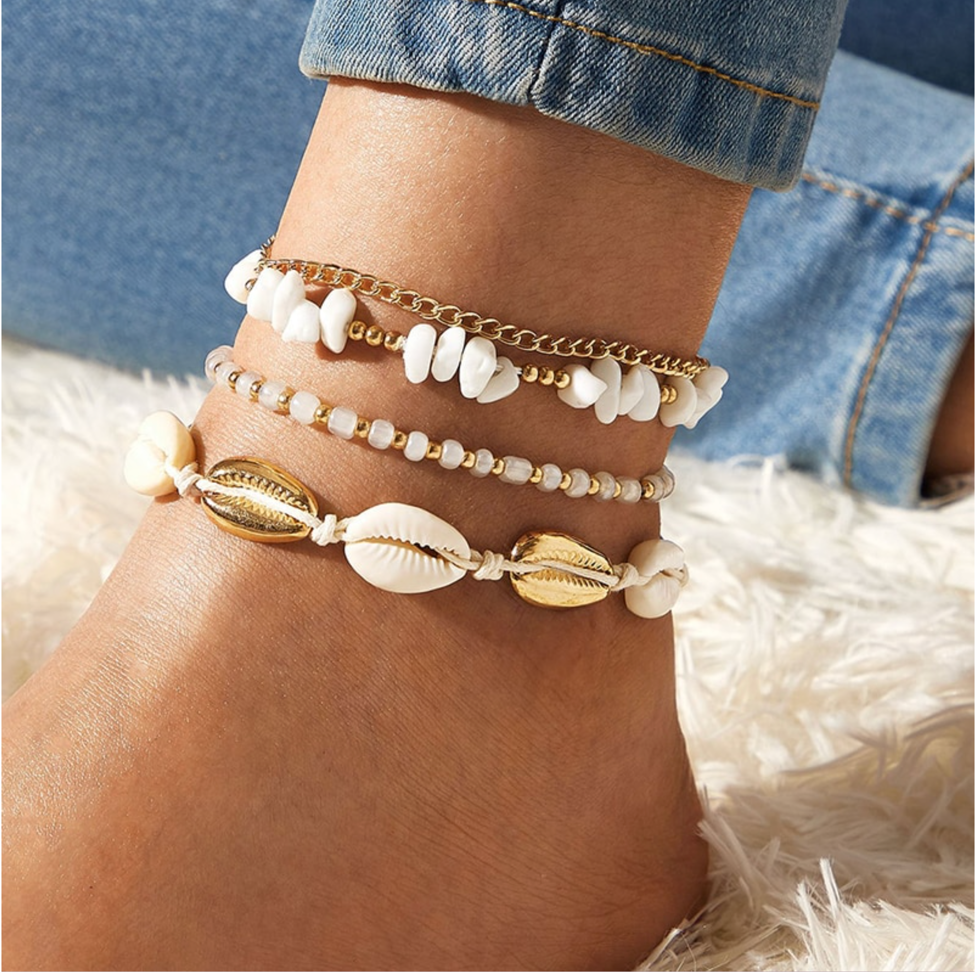 Layered white bead and shell anklets with gold-tone chains worn on an ankle