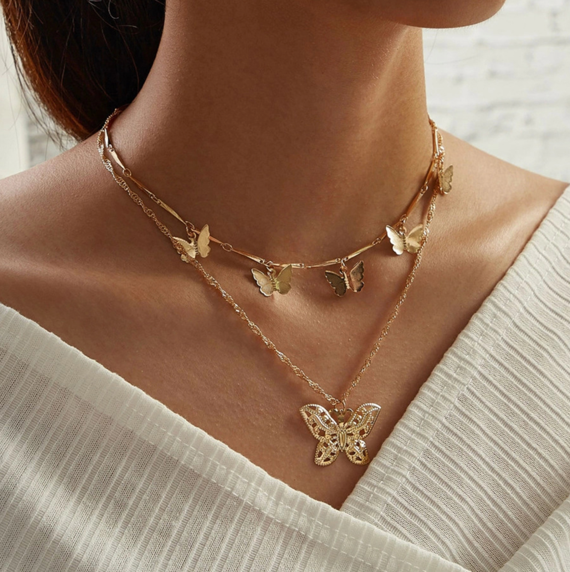 Model wearing a gold-tone butterfly charm layered necklace