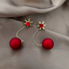 Goldtone red snowflake drop earrings laid flat on beige satin