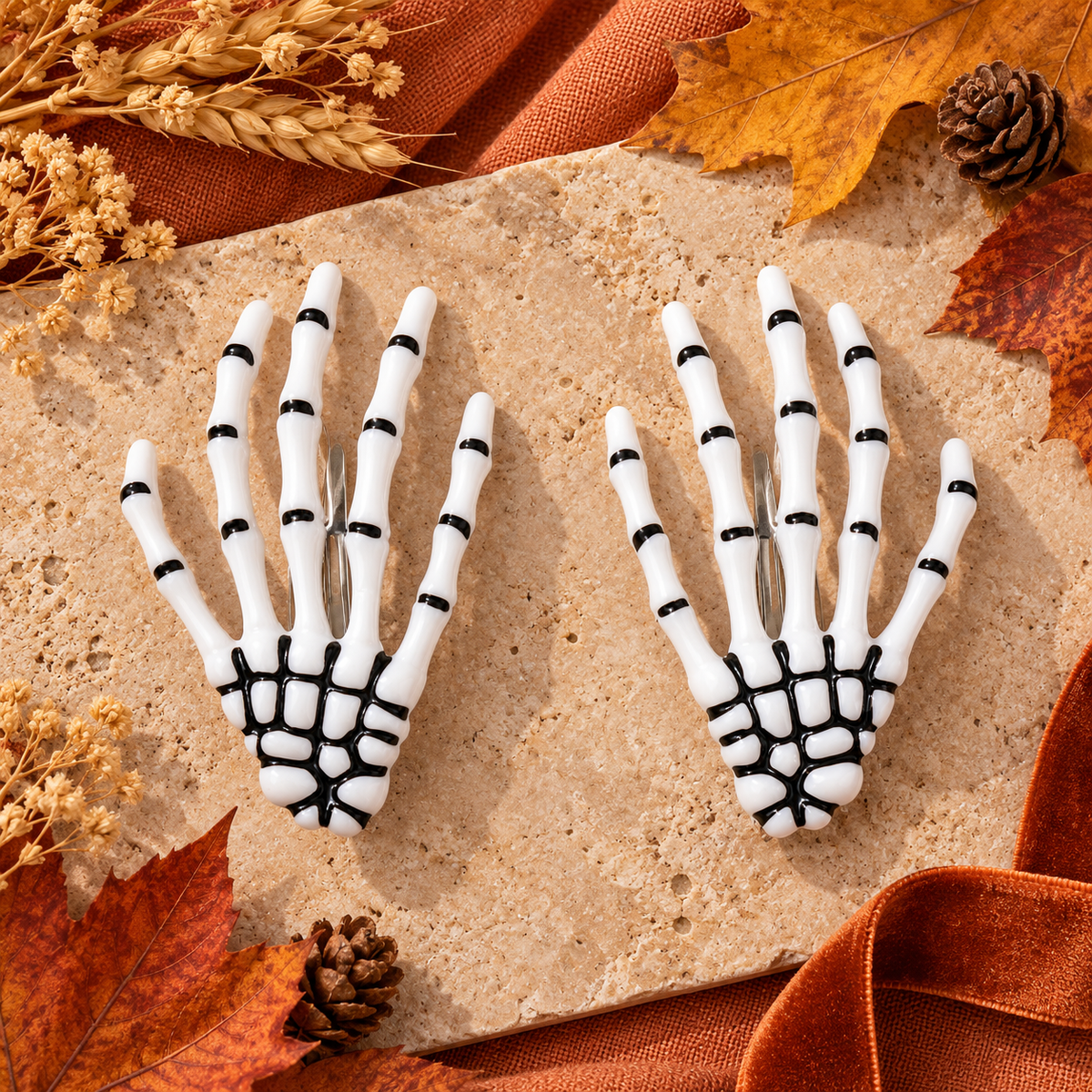 White skeleton hand barrettes arranged with autumn leaves on beige fabric
