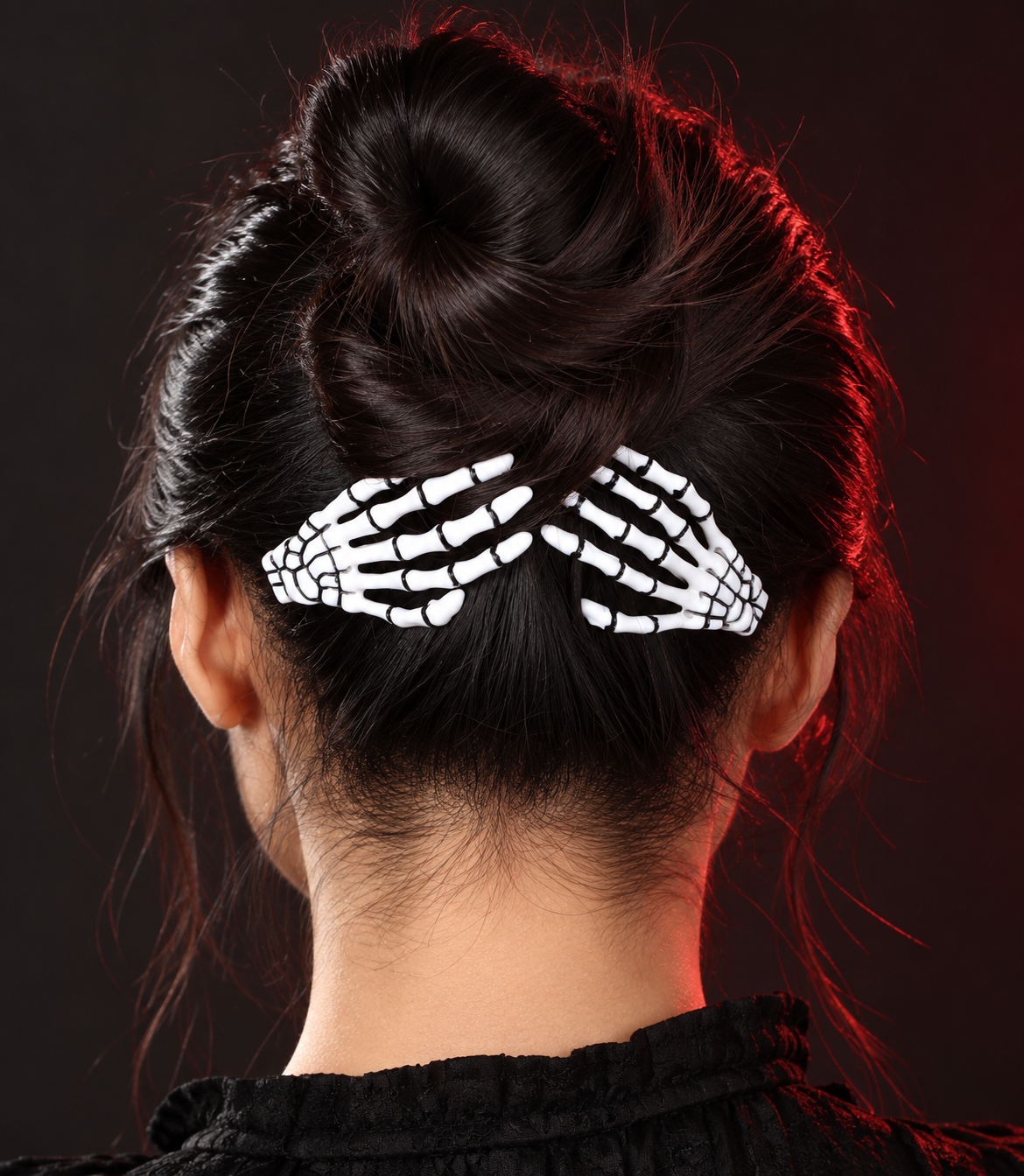 White skeleton hand barrettes worn on a dark bun in red lighting