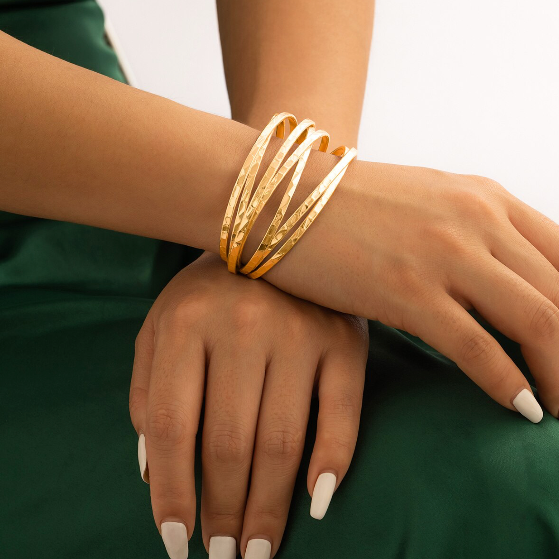 Gold bracelet on a wrist with a green background
