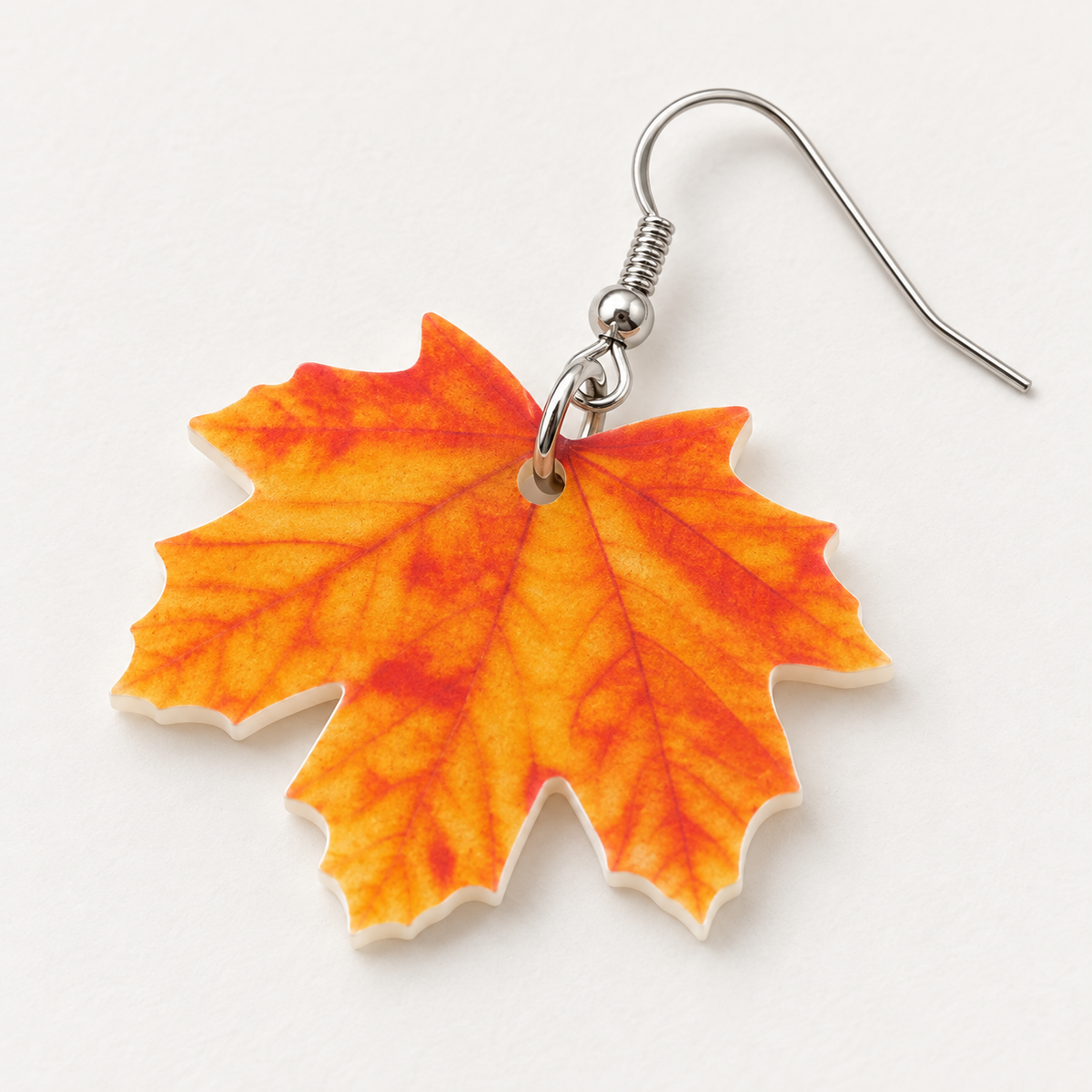 Close-up of printed acrylic maple leaf earring and silver-tone hook
