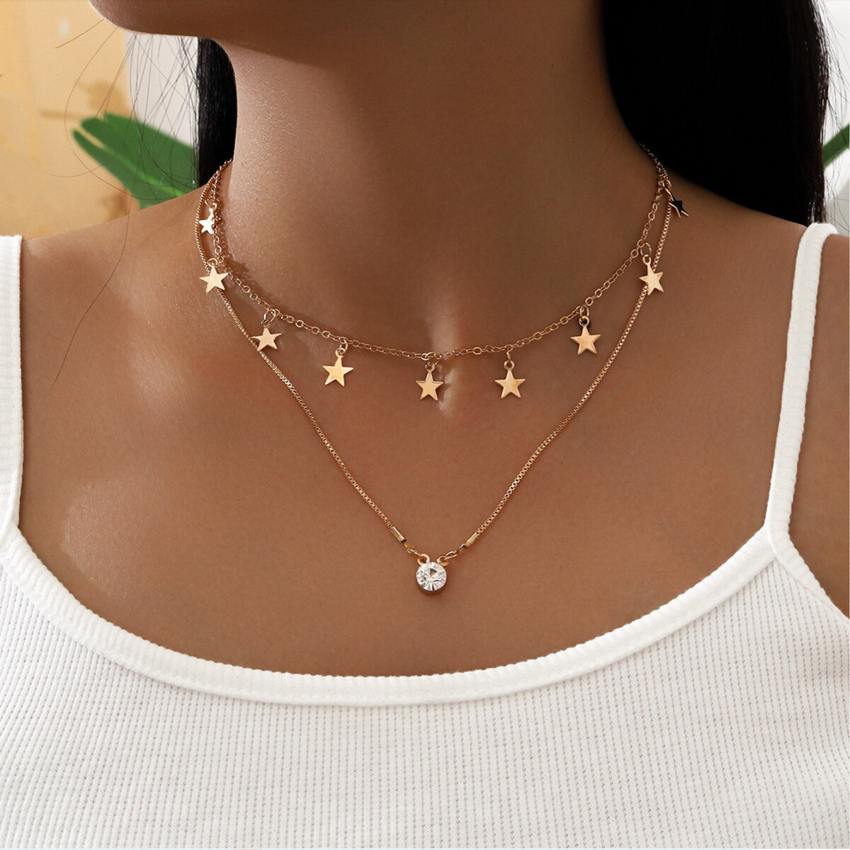 Gold-tone star charm choker and round solitaire pendant necklace, worn together