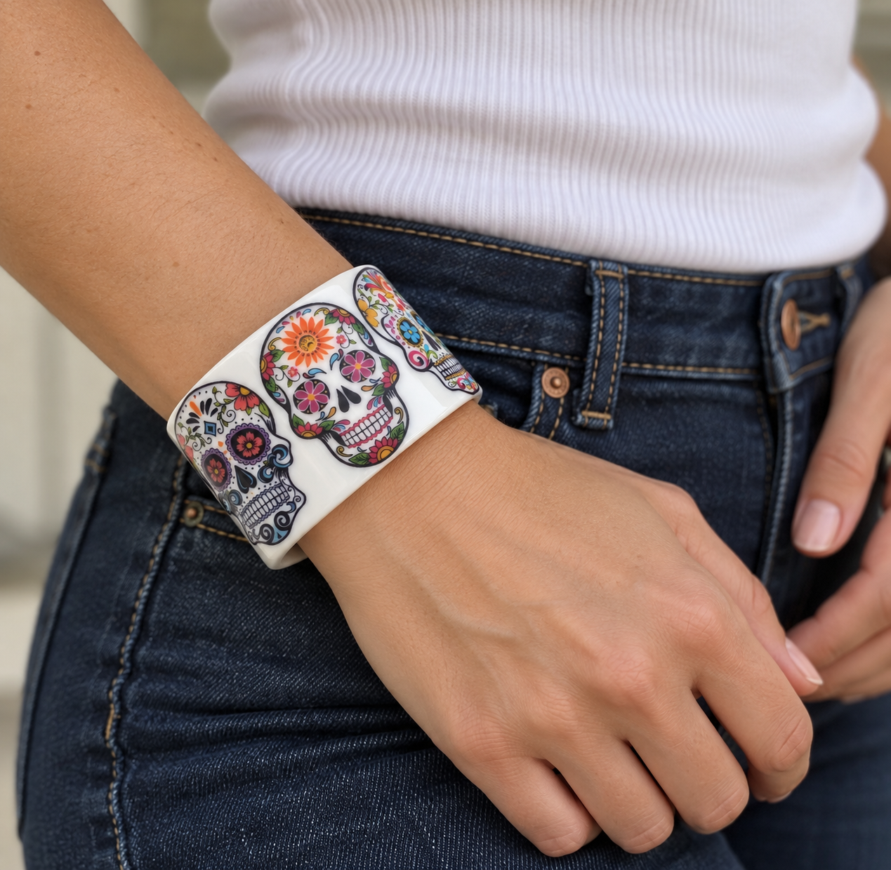 Floral sugar skull cuff worn on a wrist with denim