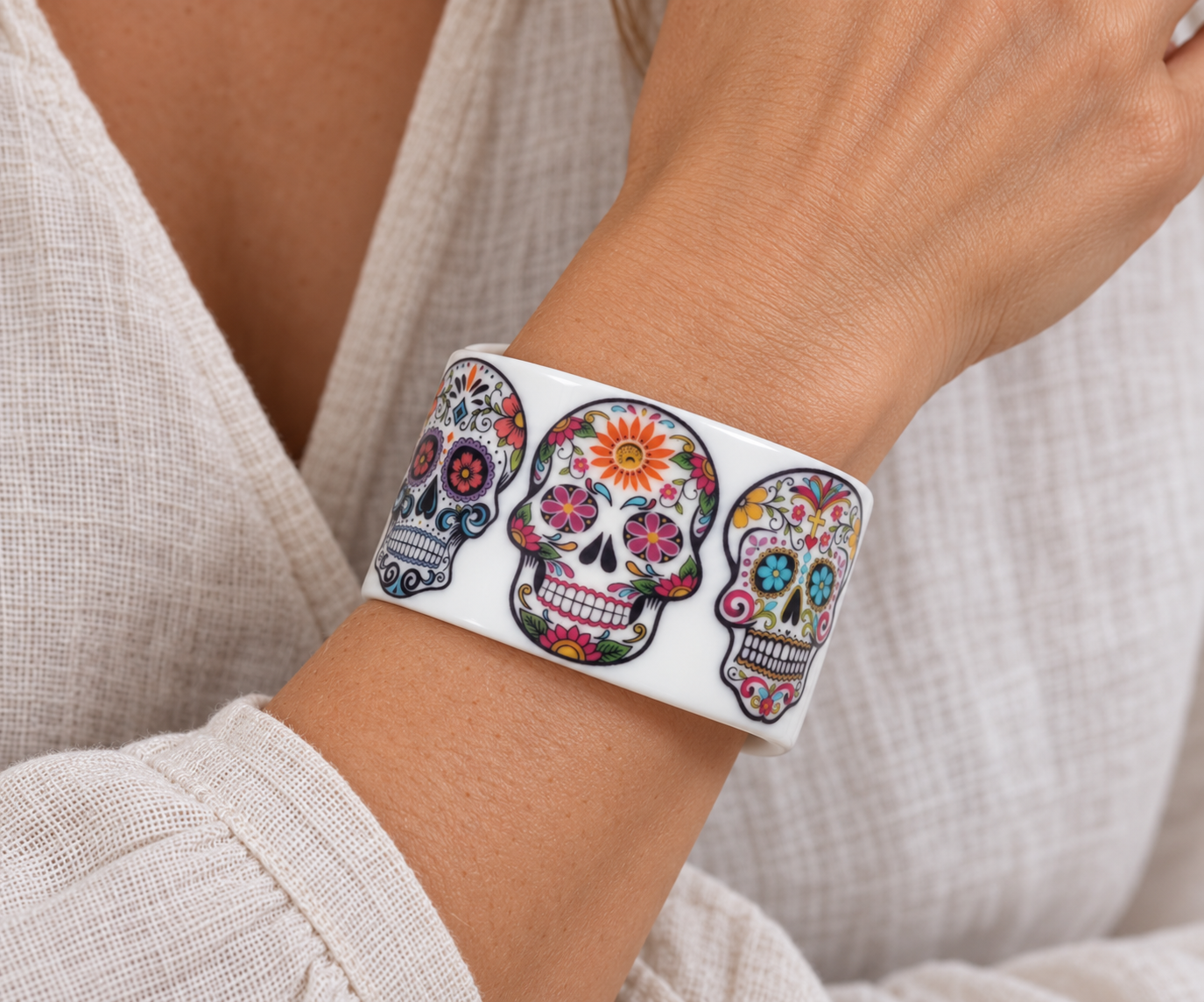 White floral sugar skull cuff on a wrist with a linen blouse