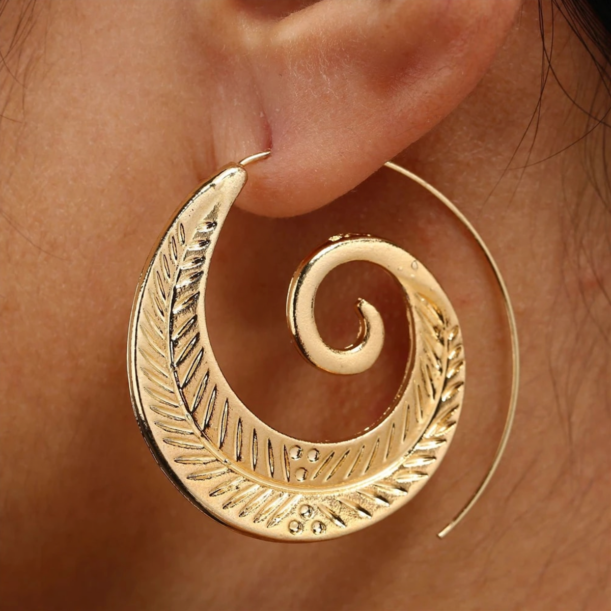 Model wearing a large goldtone spiral leaf threader earring