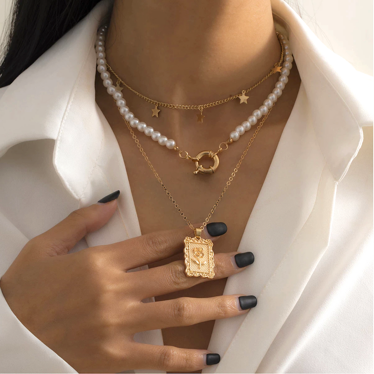 Model wearing a layered goldtone necklace with imitation pearls, stars and a rose pendant