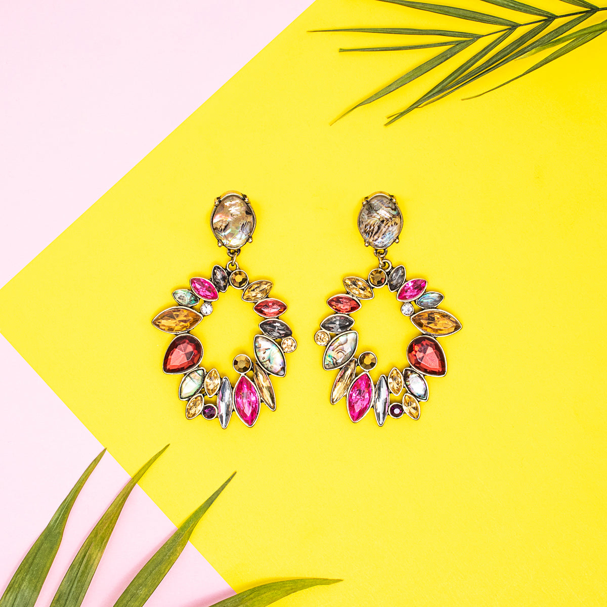 Red and yellow crystal wreath drop earrings displayed on a yellow background